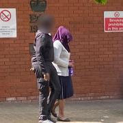 Ivy Mwangi with her head covered being escorted out of Swindon Crown Court