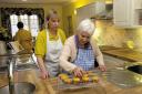 Staff member Sharon Renton oversees resident Elizabeth Thomas making cakes at the new life skills kitchen