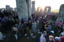 The sun glints through the stones as crowds gather at dawn for the Solstice at Stonehenge this morning