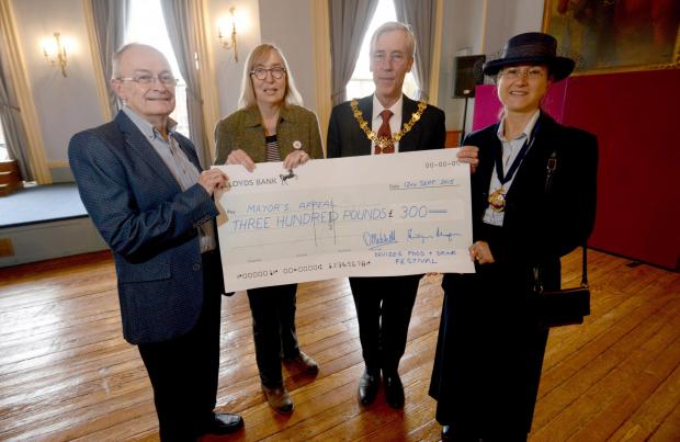 This Is Wiltshire: Devizes Food and Drink Festival treasurer Dave Mitchell and chairman Philippa Morgan present a cheque to Devizes Mayor Roger Giraud-Saunders who is accompanied by his wife Giovanna