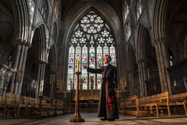 This Is Wiltshire: Very Reverend John Dobson Dean of Ripon lights a candle to mark the second anniversary of the first national coronavirus lockdown at Ripon Cathedral, North Yorkshire, ahead of the National Day of Reflection on Wednesday (PA)