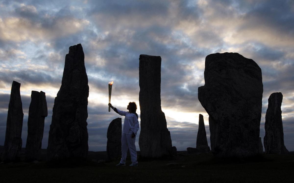 Kirsty Wade holding the Olympic Flame at the Calanais Standing Stones in Callanish as the sun rises on Day 24 of the London 2012 Olympic Torch Relay...